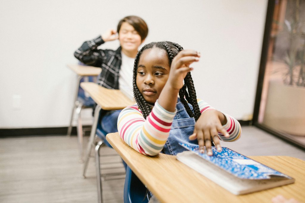 Two pupils with books in a class room.