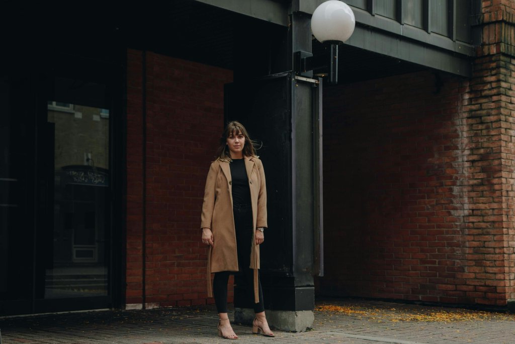 A woman standing wearing a brown 